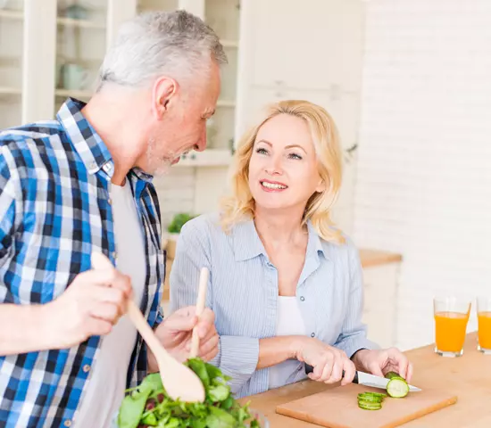 Kobieta i mężczyzna rozmawiają ze sobą podczas wspólnego przygotowywania posiłku w kuchni